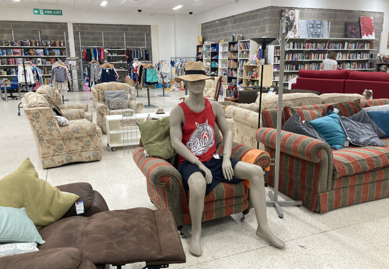 Holidays by Judy Darley. Shows a mannequin sitting in a charity shop dressed for the beach.