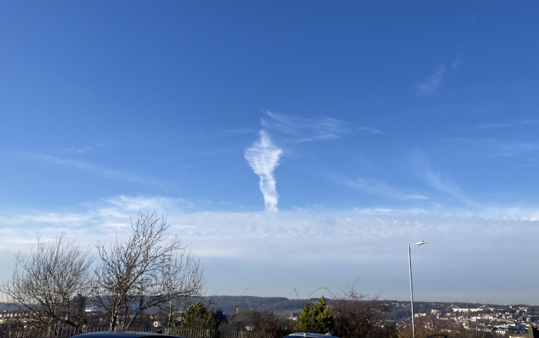 Look up cloud formation shaped like a hand with a pointing finger against a blue sky